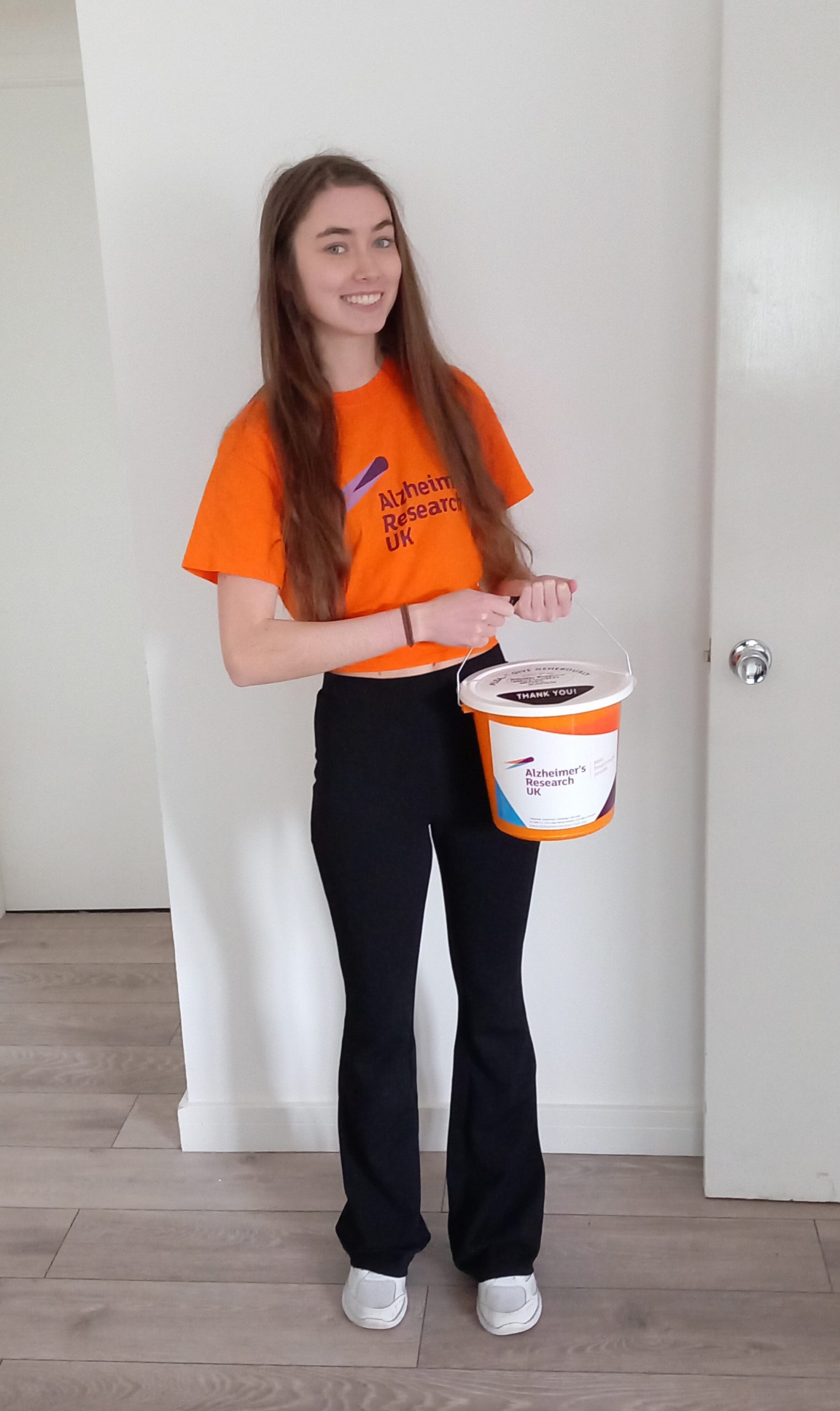 Image of Alicia Cumberland holding a charity bucket for Alzheimer's Research UK