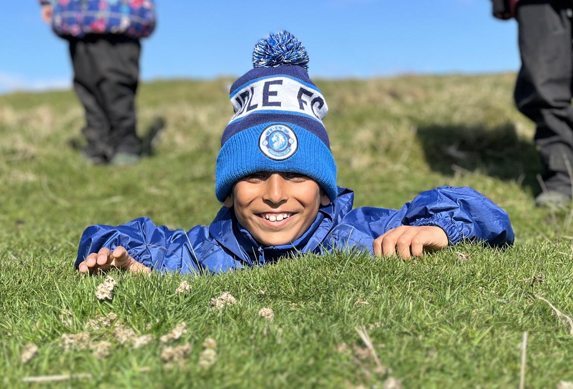 Image of a Bradford Grammar Junior School pupil laying on the grass at a school residential trip