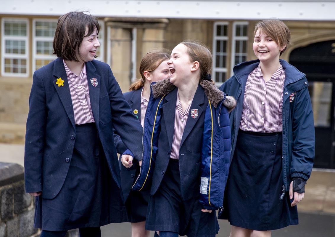 Four Bradford Grammar Junior School pupils walking and laughing outside the school