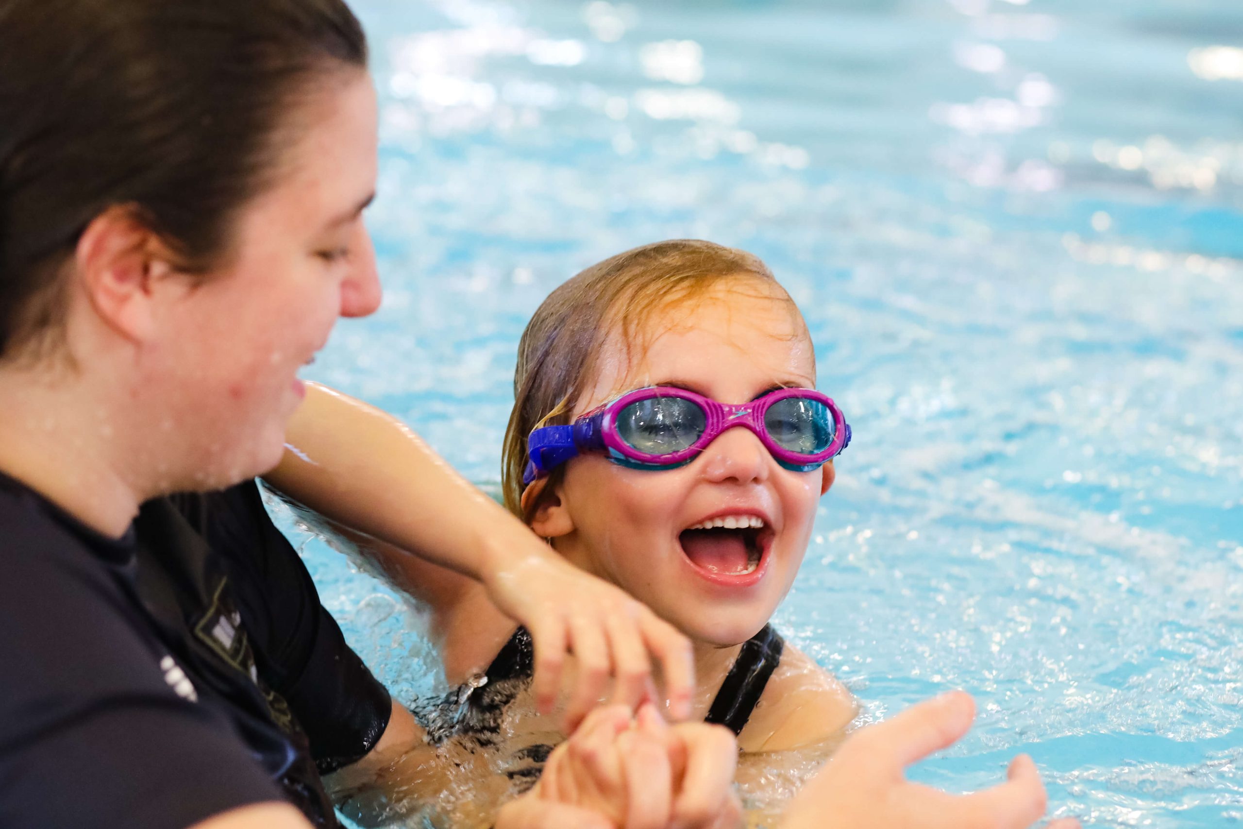 A pupil wearing goggles and a teacher in the swimming pool